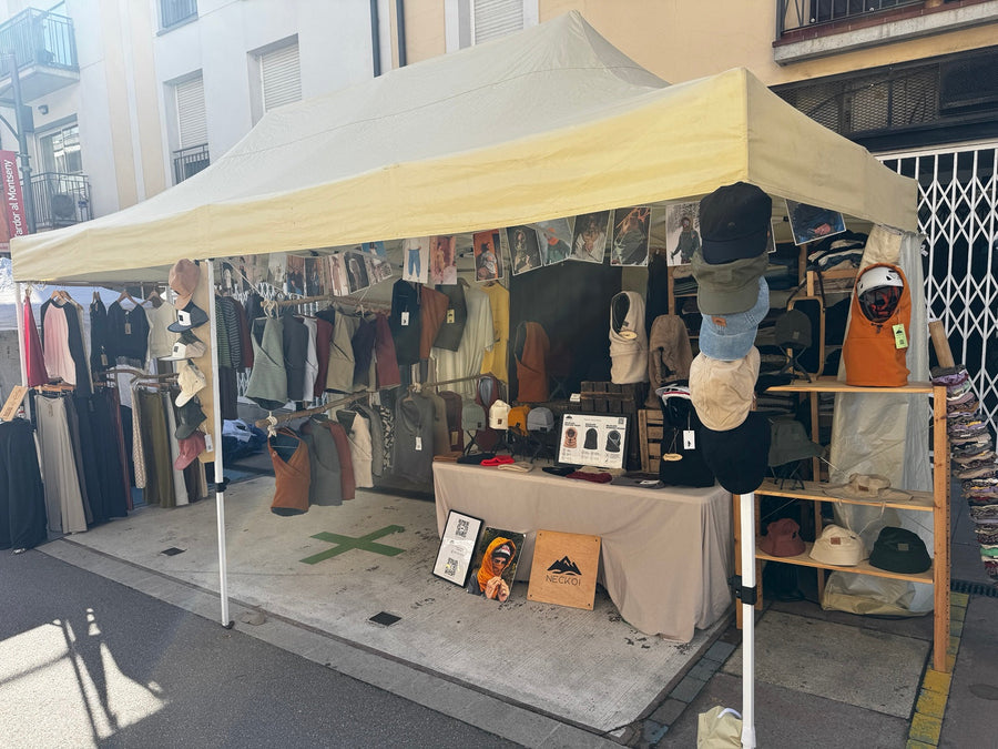 Una parada con prendas y un expositor de balaclavas, gorras y gorros Neckoi