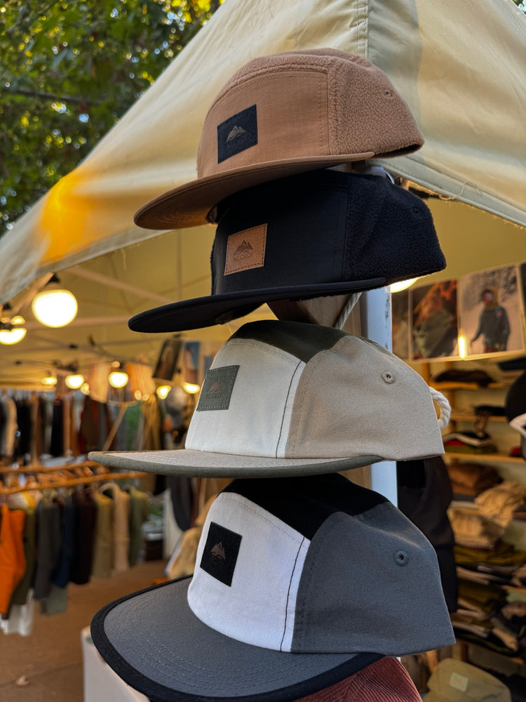 Détail de casquettes Neckoi de différents tissus et couleurs sur une foire